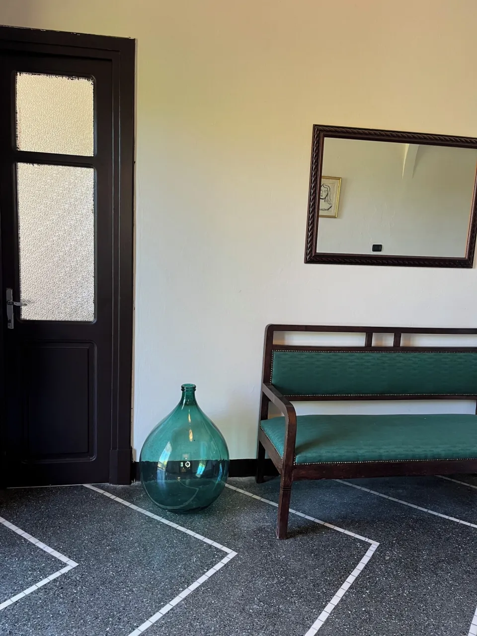 Room with a black door, green sofa and mirror