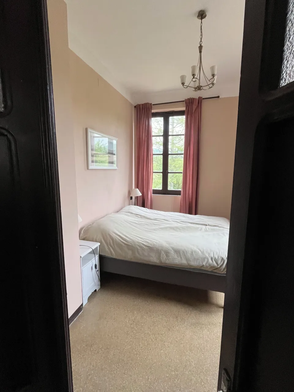 Bedroom with a bed, nightstand and a window with curtains