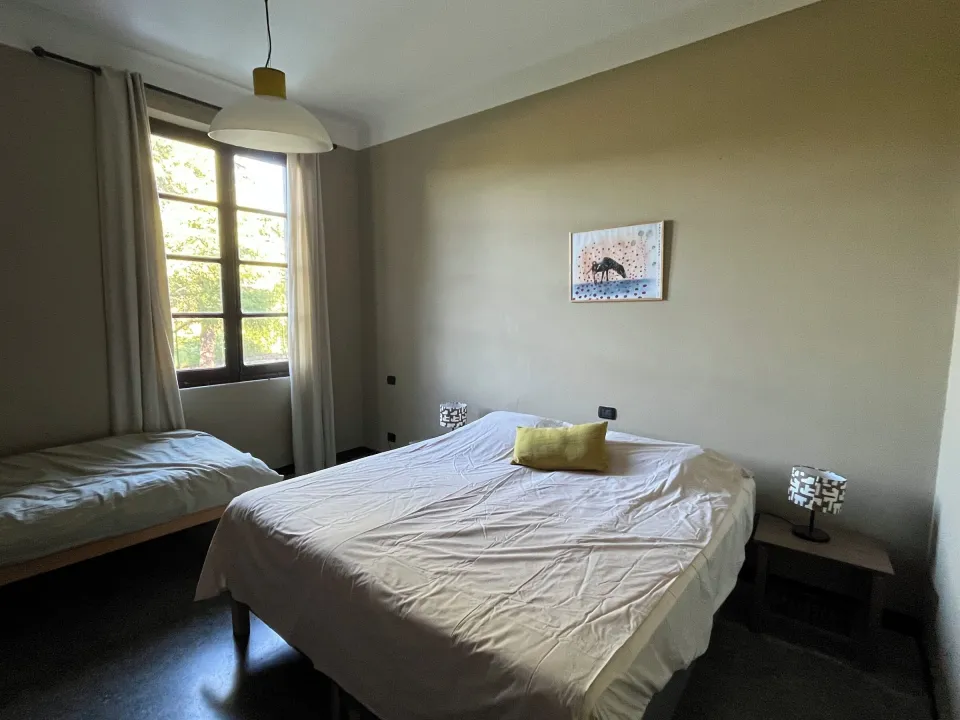Room with two single beds, a wall lamp and a painting