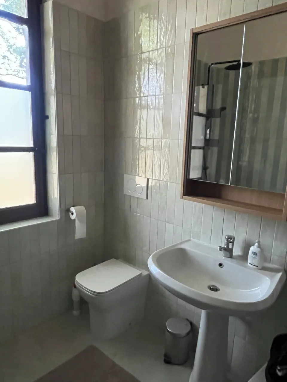 Bathroom with a toilet, sink, mirror and window
