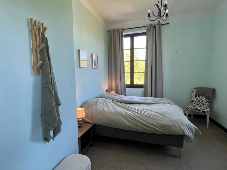 Bedroom with a bed, chair and wooden coat rack