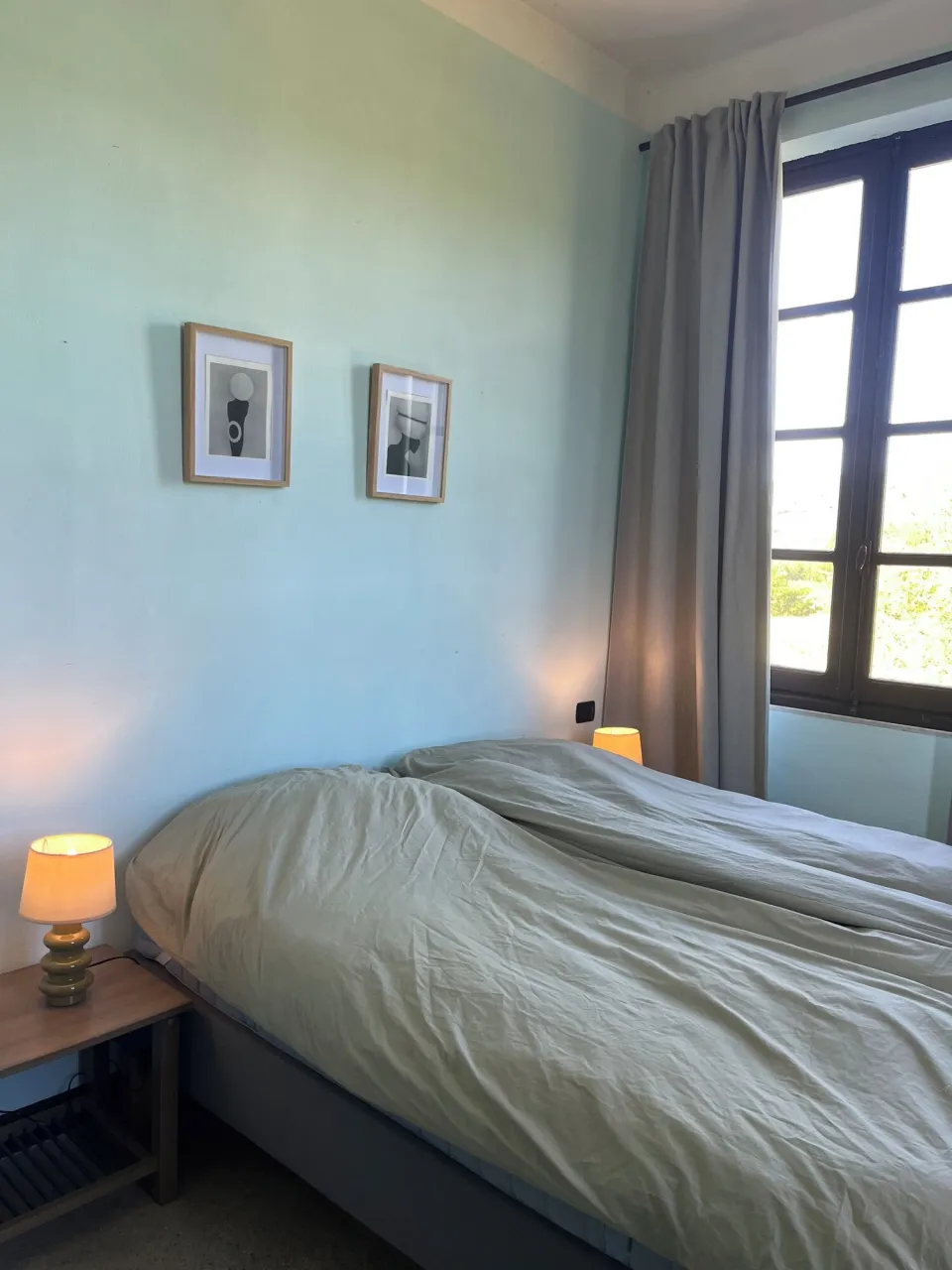 Bedroom with a bed, framed photos and a bedside lamp