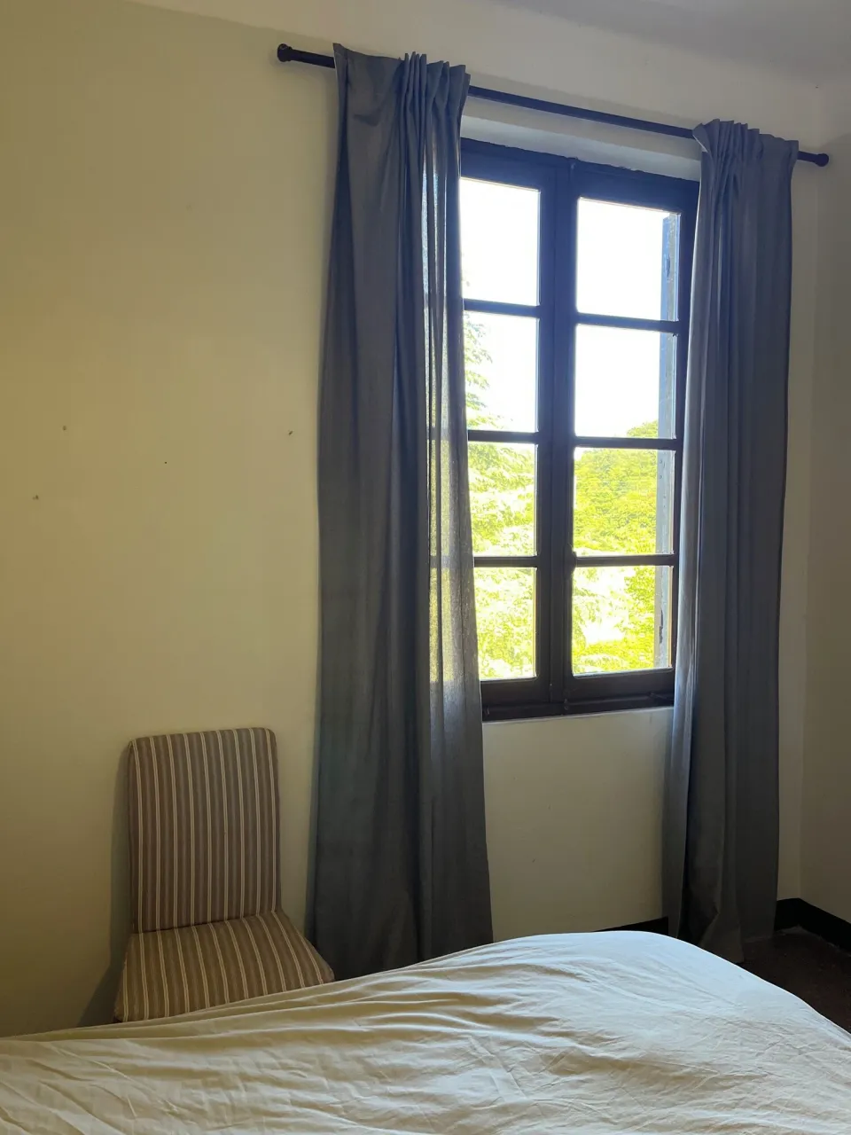 Room with a bed, chair and a window with curtains