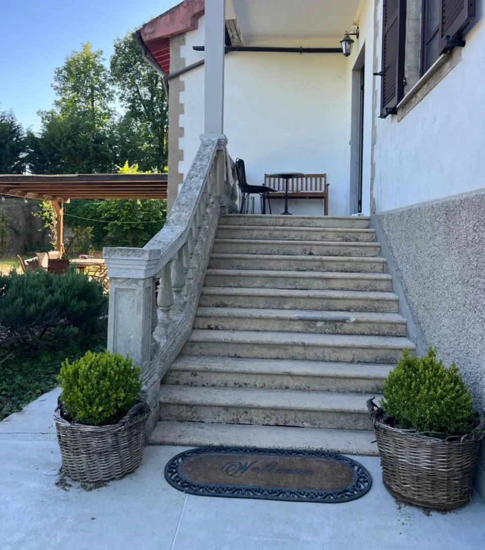 Stone steps to the building with a wooden bench and potted plants